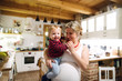 © Halfpoint - Beautiful pregnant woman carrying a toddler boy in the kitchen at home.