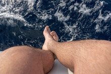 Hanging Legs And Feet Of A Man On A Boat