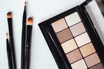 Top view on palette of shadows and makeup brushes on a white background close up