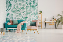 Pink Chair Next To Blue Couch Against Green Wallpaper In Spacious Flat Interior With Stool. Real Photo