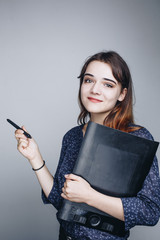 Close up portrait of beautiful young brunette woman with tablet pen and graphic tablet posing against grey background in the studio. Graphic designer