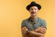 Happy handsome caucasian man with moustache wearing hat and stripped shirt isolated over yellow background. Looking at camera.