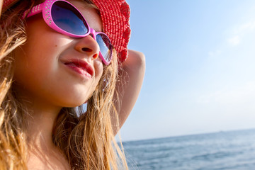 Portrait of child girl with summer hat and sunglasses relax on sea sunlight