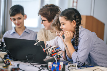 curious smart caucasian pupils kids with female teacher enjoying science robotics lessons in technic