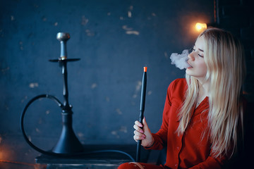 girl smokes  hookah / beautiful glamorous girl in red dress smokes a hookah, the sexy model in a night club smokes