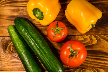 Cucumbers, tomatoes and sweet pepper on wooden table. Top view