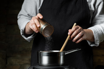 Wall Mural - Adding pepper and salt for cooking tomato sauce in metal saucepan by chef hands, steps process recipe.