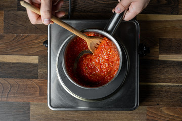 Wall Mural - Cooking tomato sauce in metal saucepan by man cook hands, steps process on black background copy text recipe.