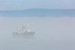 Fishing boat in thick fog on the background of mountains