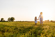 © LIGHTFIELD STUDIOS - mother and daughter walking in green meadow with sunset on background