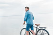 © LIGHTFIELD STUDIOS - handsome man walking with bicycle near the sea
