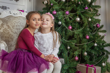 Teenage girls having fun under Christmas tree with gifts