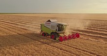 Aerial shot of a combine harvester in action on wheat field.