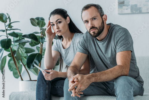 Fotomural sad stressed couple with pregnancy test sitting and looking at camera