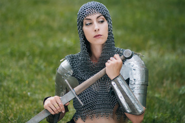 Medieval girl warrior, in a chain mail hood with a sword in his hand. A woman in European armor. Viking. Fantasy