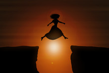 Woman Wearing A Dress And High Heels Jumps Over A Gap Between Two Rocks During Sunset