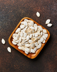 Wall Mural - Raw pumpkins seeds on brown background. Top view.