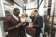 © xartproduction - successful and young businessmen in the elevator business center rides to work