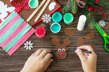 Wall Mural - The child draws details Santa and Reindeer stick gift. Handmade. Project of children's creativity, handicrafts, crafts for kids.