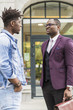 © xartproduction - two young and stylish African American men in the city smiling and talking. father and adult son relationship