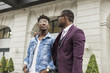 © xartproduction - two young and stylish African American men in the city smiling and talking. father and adult son relationship
