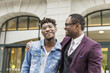 © xartproduction - two young and stylish African American men in the city smiling and talking. father and adult son relationship