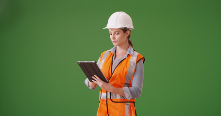 Young woman construction manager using tablet device on green screen