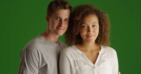 Wall Mural - Cute millennial couple standing together smiling at camera on green screen