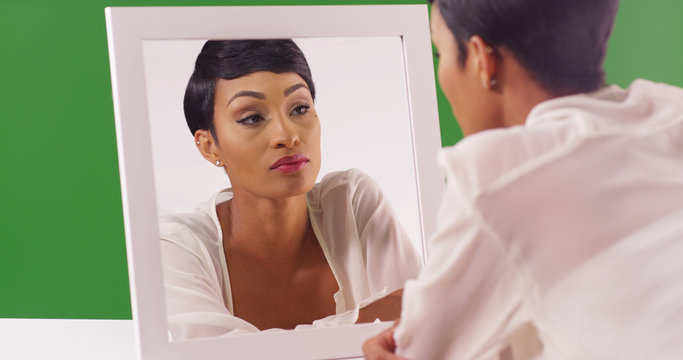 Wall Mural -  - Lovely black woman looking at her reflection in mirror on green screen