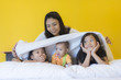 © Sirirat Makprasert - Babysitting playing with three playful kids carrying on the bed; widow young woman and child are enjoying fun time indoor in modern yellow bed room; mother and three daughter; Happy family