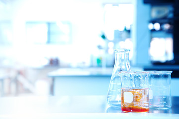 Wall Mural - flask beaker with orange solution in science research education laboratory background