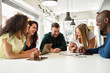 © javiindy - Multi-ethnic group of young people studying together on white desk