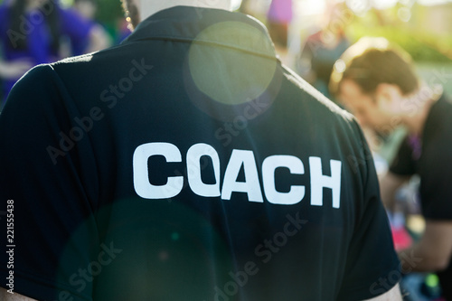Fotomural Sport coach in black shirt with white Coach text on the back standing outdoor at