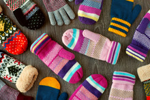Mittens For Winter. View From Above. Many Multicolored Mittens On A Wooden Background. Warm Clothing For Hands In The Cold Season.