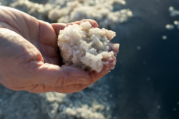 salt lake, collection of salt, hand with salt in the foreground, background salt lake