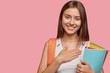 © wayhome.studio  - Friendly pleased thankful young hipster carries rucksack, holds colourful folder with papers, keeps hands on chest, has tender smile, isolated over pink background with copy space for your text