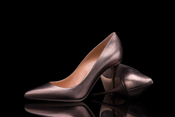 Wall Mural - Elegant women's high heel shoes in bronze leather on a black background. Women's high-heeled shoes.