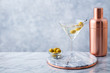 © annapustynnikova - Martini cocktail with olives and bar shaker on marble table background. Copy space.