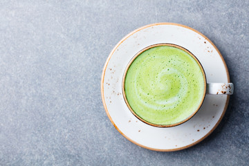 Matcha, green tea latte in a cup. Grey stone background. Top view. Copy space.