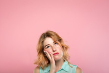 Facial Expression. Low Mood And Emotion. Bored Unimpressed Disinterested Woman Looking Up. Young Beautiful Blond Girl Portrait On Pink Background.