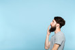 man looking sideways and is shocked or impressed by smth on the left. free space for advertisement or text. portrait of a bearded guy on blue background.