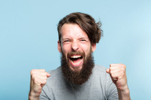 Yes Success And Achievement. Happy Overexcited Enthusiastic Exhilarated Guy Making A Win Gesture And Screaming. Thrilled Man Portrait On Blue Background.