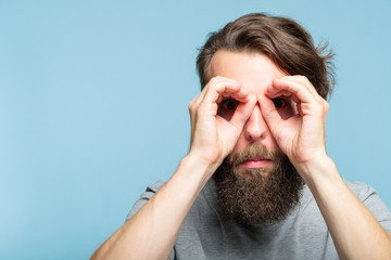 funny ludicrous joyful comic playful man pretending to look through binoculars made of hands. portra
