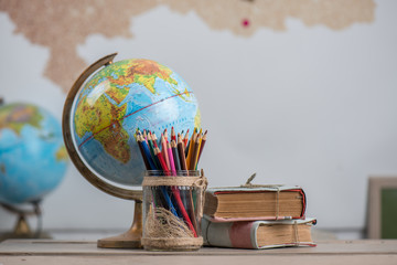 school background, books, globe and color pencils are on the desk