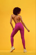 © Mike Orlov - Beautiful young and fit woman. Isolated on a yellow background in a pink sportswear