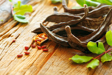 Carob. Healthy Organic Sweet Carob Pods With Seeds And Leaves On A Wooden Table. Healthy Eating, Food Background