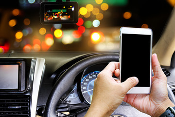 Man using a smart-phone while driving a car at night. CCTV car camera. Technology concept.