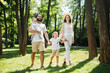 © Leika production - Warm sunny day. Handsome father, beautiful mother and two kids dressed in the white casual clothes happily walks in the park.