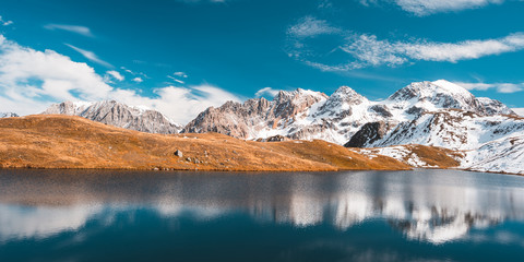 Wall Mural - Colorful sunlight behind majestic mountain peaks of the Italian - French Alps, viewed from distant. Fog and mist covering the valleys below, autumnal landscape, cold feeling.