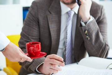 Young secretary brings coffee to the male boss. Service staff. Coffee time concept and time for a break.